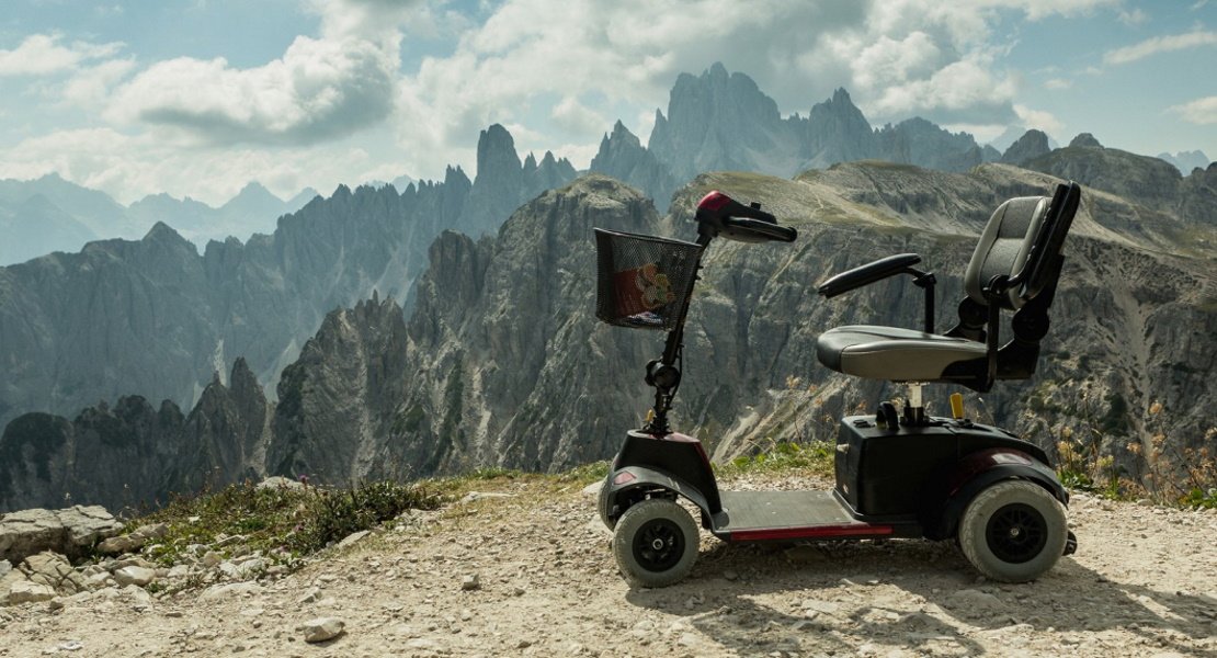 Header-red-mobility-scooter-sitting-at-the-top-of-a-mountain