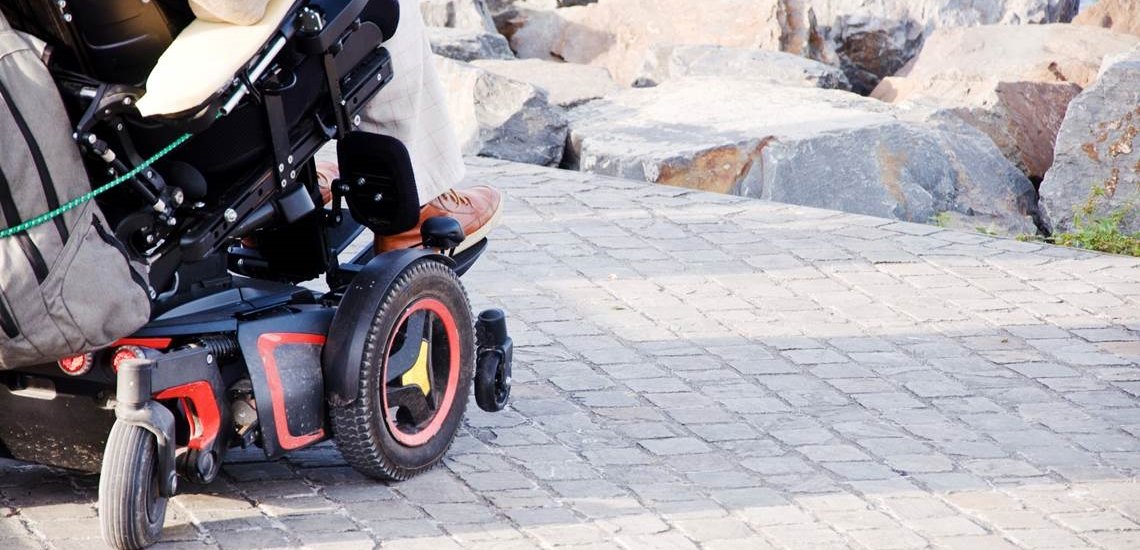 A Person In A Power Wheelchair Parked On A Jetty.