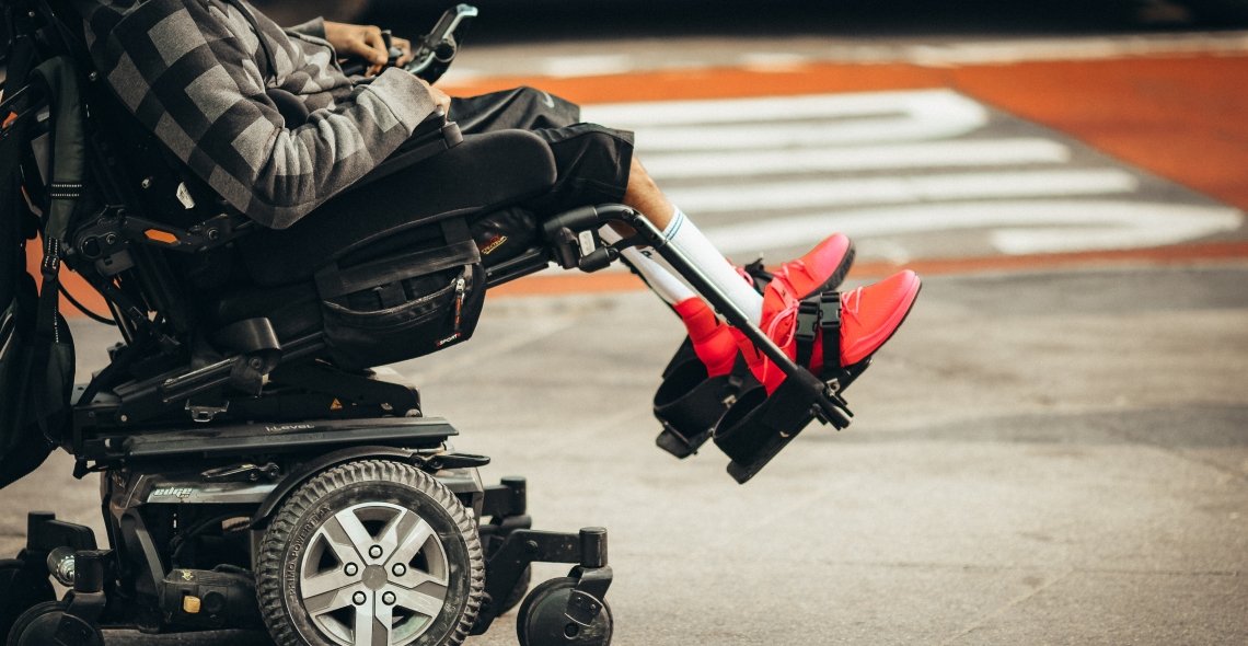A Person With Gray And Black Sweater On A Power Wheelchair