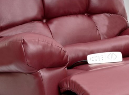 A close up of the seat of a red lift chair with a remote resting on it