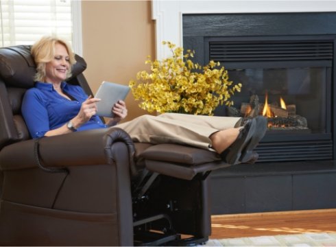Happy woman sitting on a Golden Technologies MaxiComfort® lift chair recliner while she looks at her tablet