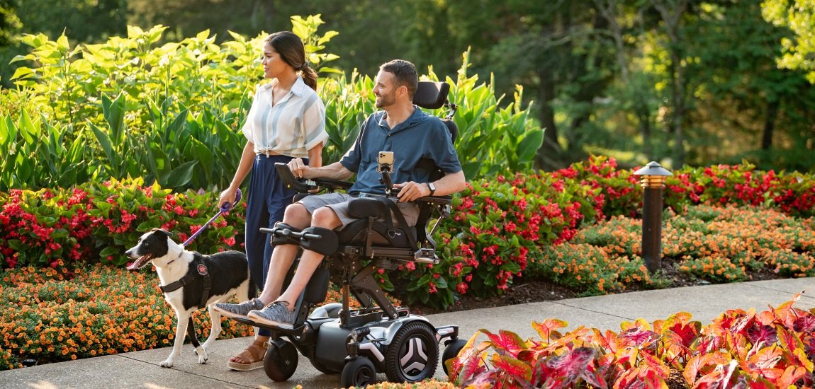 A man and a woman going through a garden with a dog by their side